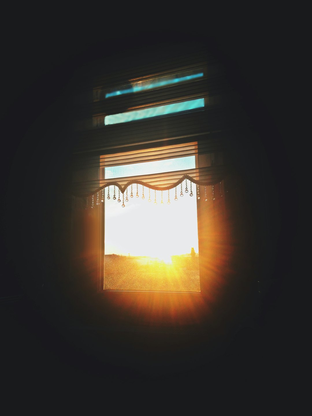 Beaded valance hanging over a window with glowing landscape views.