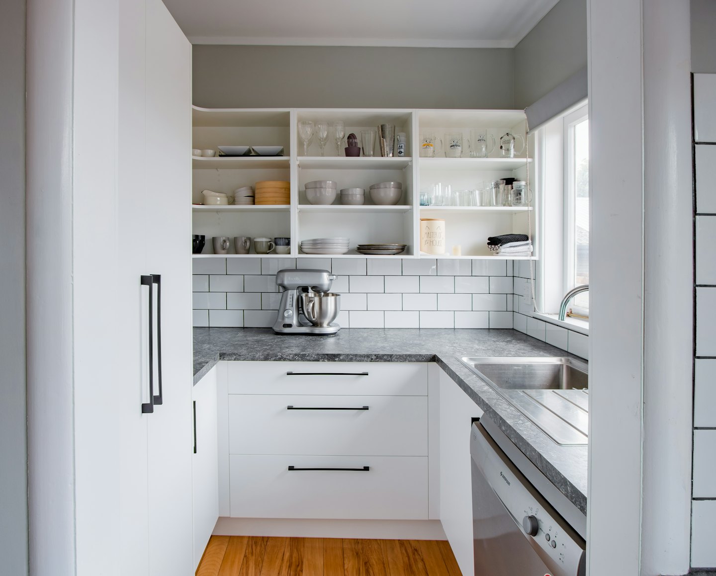 Modern kitchen with white cabinets and organized open shelving.